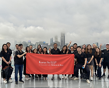 Karas So team holding Karas So LLP banner